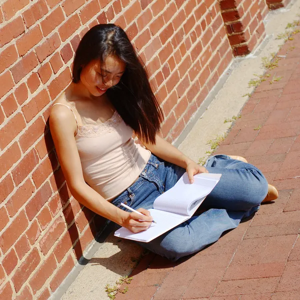 Mädchen schreibt in Notizbuch — Stockfoto