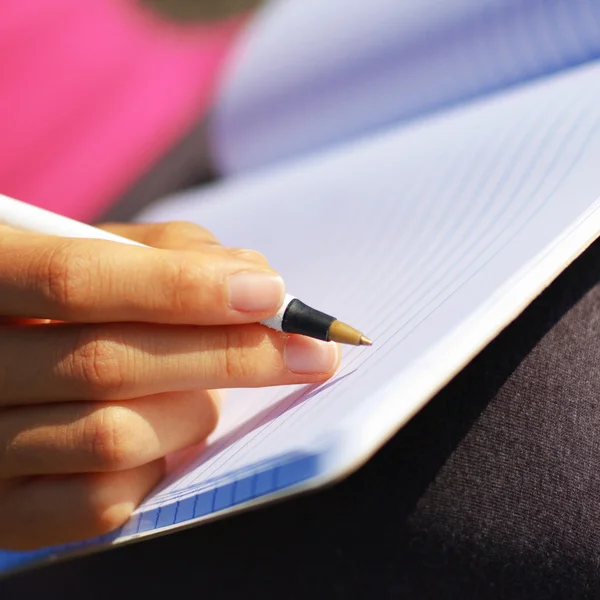 Mädchen schreibt in Notizbuch — Stockfoto