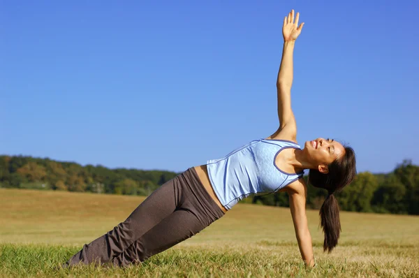 Mädchen praktiziert Yoga im Feld Stockbild