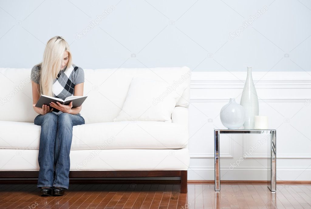 Young Woman Sitting on Sofa Reading