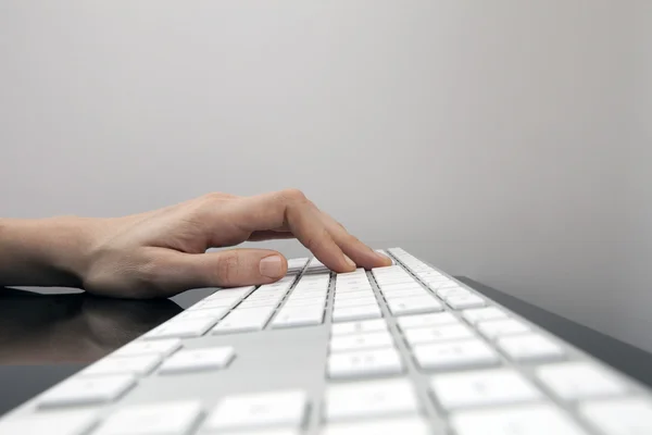 Zenske ruku na plochá bílá klávesnice — Stock fotografie