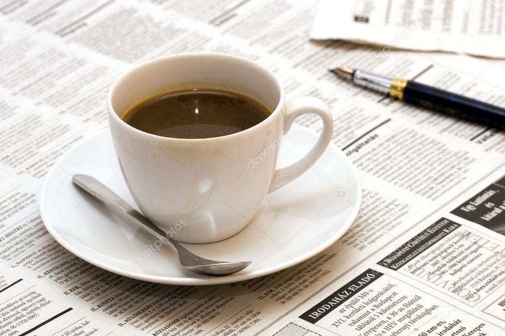 Cup with coffee on newspaper