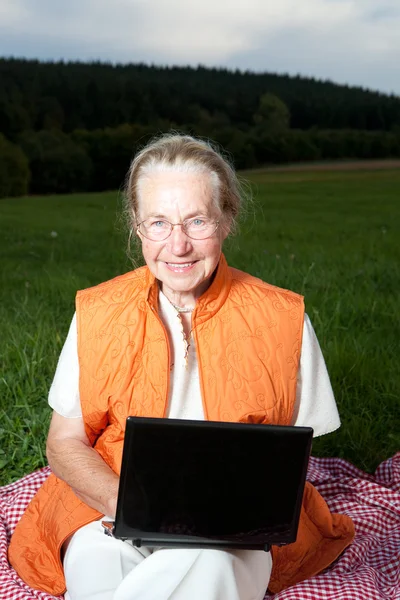 Dizüstü bilgisayar kullanan yaşlı bir kadın.