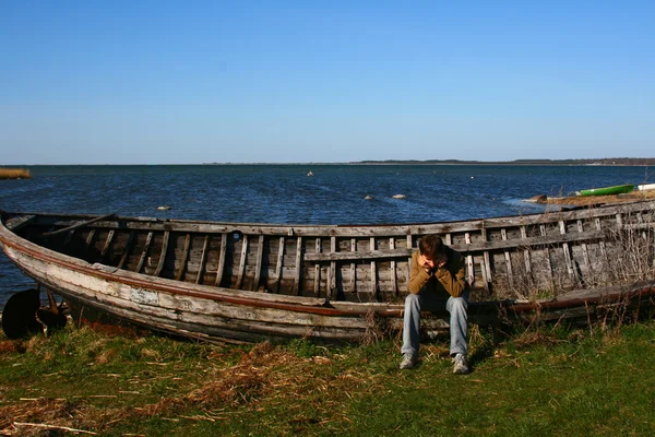 stock image Sad man near the old wooden boat