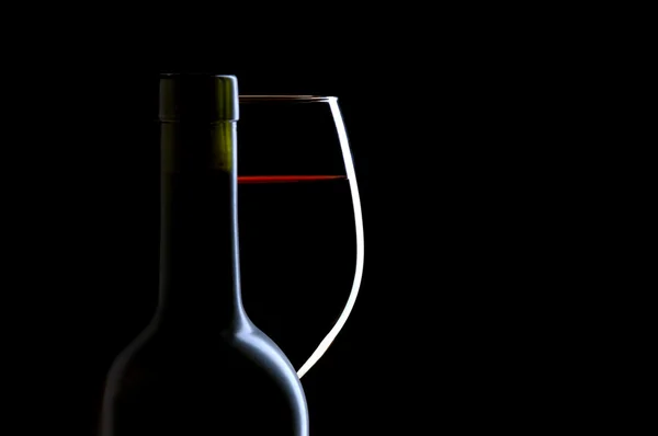 Verre et bouteille de vin rouge sur noir — Photo