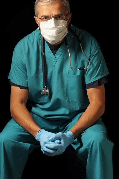 Середнього віку лікар сидить над чорним — стокове фото