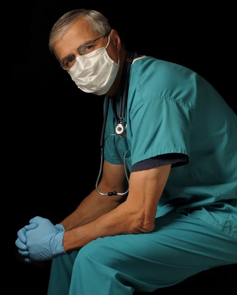 Middle aged doctor seated over black — Stock Photo, Image
