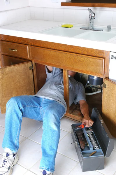 Mannen under diskbänken med verktygslådan — Stockfoto