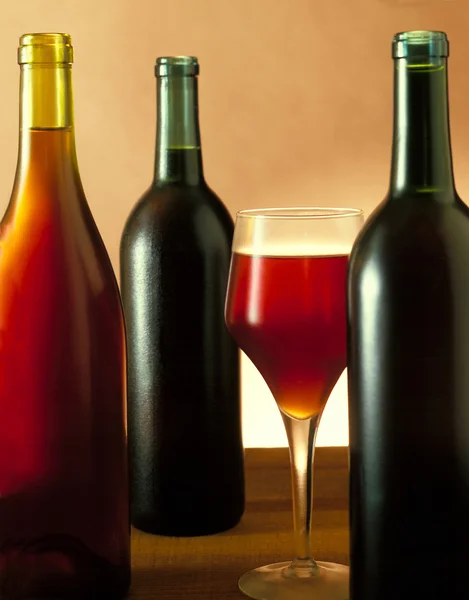 Три бутылки вина и стекло — стоковое фото