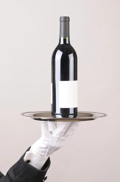 Butler håller vinflaska på bricka — Stockfoto