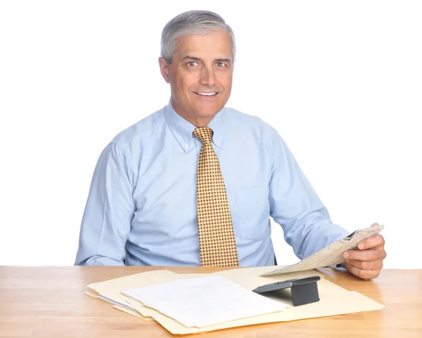 Улыбающийся бизнесмен сидит за столом — стоковое фото