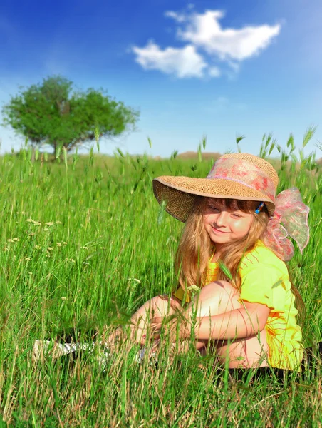 Marzy dziewczynka siedzi w trawie — Zdjęcie stockowe