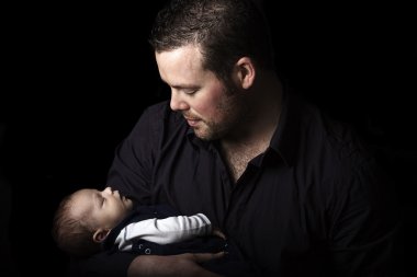 Doting father holds his new born son clipart