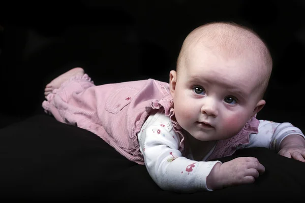 Schattige babymeisje in roze op een zwarte laag belangrijke achtergrond — Stockfoto