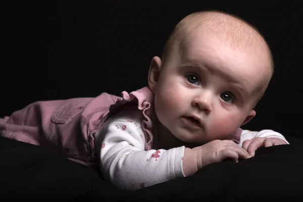 Bayi perempuan cantik berbaju merah muda dengan latar belakang kunci hitam rendah — Stok Foto