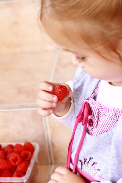 Little girl holding a raspberry — Stock Photo, Image