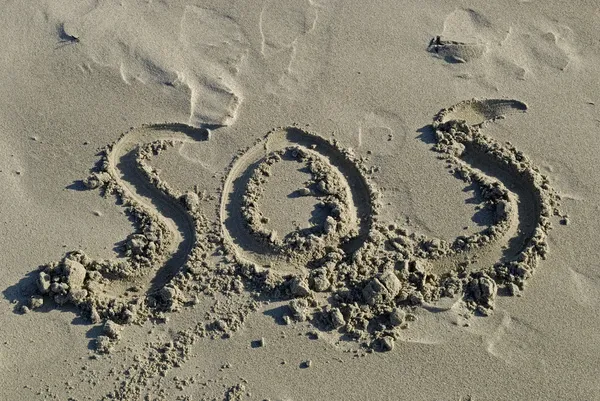 SOS написано піском Стокове Зображення