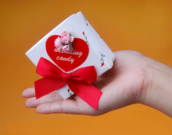 Red heart decoration with wedding candy box in hand — Stock fotografie