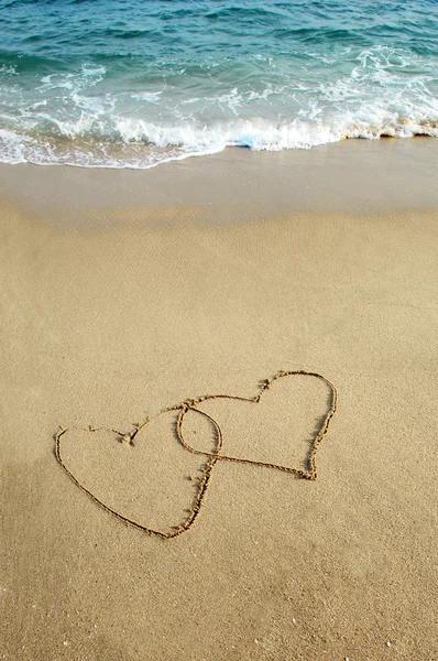 Два сердца, нарисованные на пляже — стоковое фото
