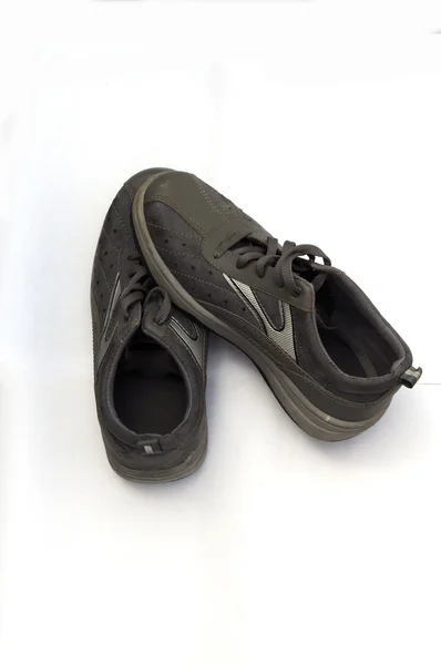Une paire de vieilles chaussures de sport noires sur fond blanc . — Photo