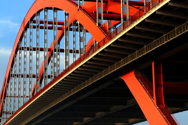 stock image The orange colored steel cable stayed bridge high in the blue sky.