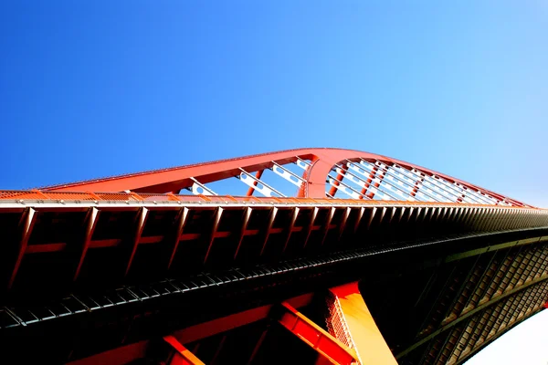 Το πορτοκαλί έγχρωμο χάλυβα καλωδιωτή γέφυρα που είναι υψηλή στο μπλε του ουρανού. — Φωτογραφία Αρχείου