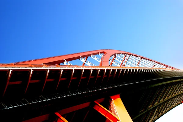 stock image The orange colored steel cable stayed bridge high in the blue sky.