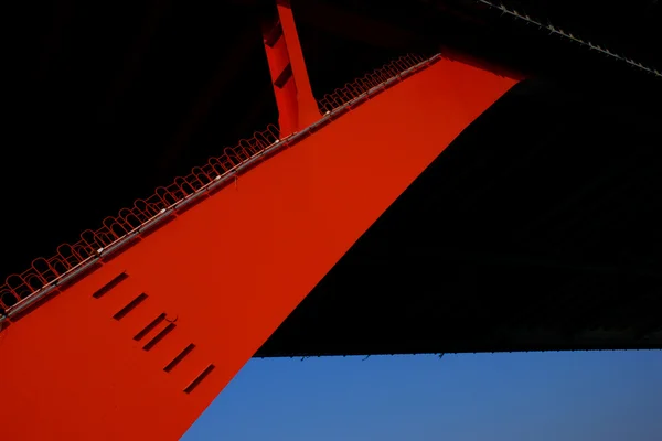 Die orangefarbene Stahlseilbrücke hoch in den blauen Himmel. — Stockfoto