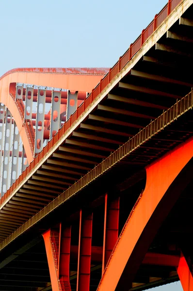 Die orangefarbene Stahlseilbrücke hoch in den blauen Himmel. — Stockfoto