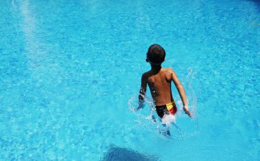 Boy playing in swiming pool clipart