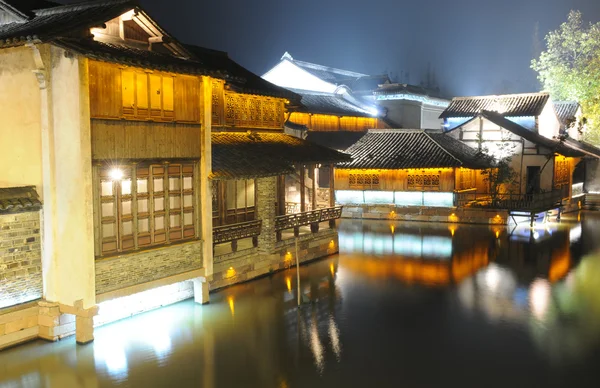 Les bâtiments chinois de la ville aqueuse près de la rivière de la nuit pittoresque Photo De Stock
