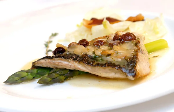 Sea bass with an asparagus and raisin — Stock Photo, Image
