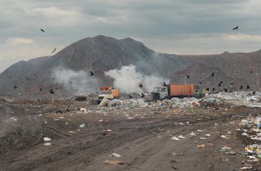 Garbage trucks on a city dump of dust clipart