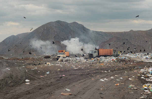 Garbage trucks on a city dump of dust