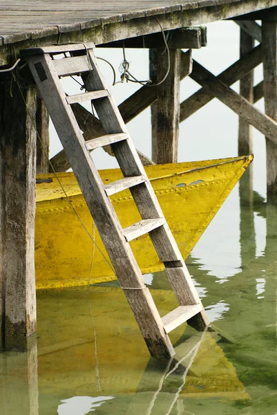 Gelbes Boot unter dem Dock lizenzfreie Stockfotos