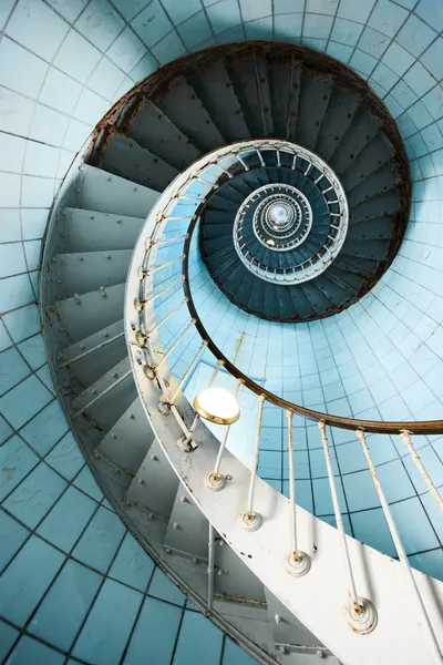 Спиральная лестница поднимается с голубой плиточной стеной — стоковое фото