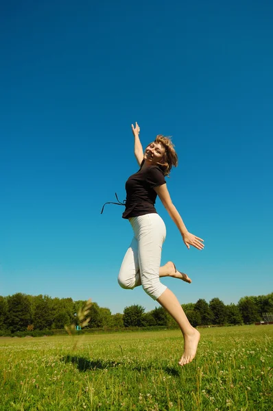 Skákání dívka proti modré obloze — Stock fotografie