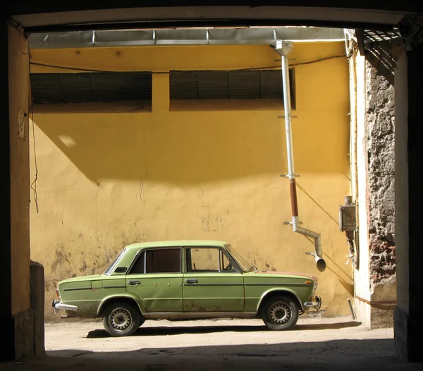 En gammal bil parkerad i arch-gården väl. — Stockfoto
