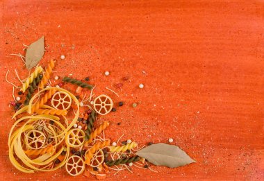 Pasta and spices on orange backgroung clipart