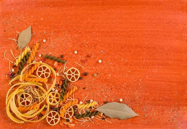 Stock image Pasta and spices on orange backgroung