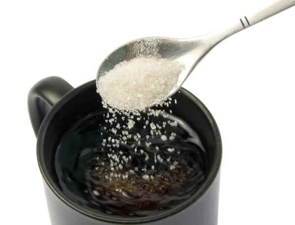 Сахар падает с ложки в чашку — стоковое фото