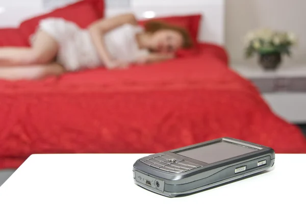 Mobiele telefoon met wazig slapende vrouw — Stockfoto