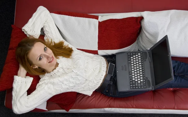 Vakker kvinne på sofa med bærbar PC – stockfoto