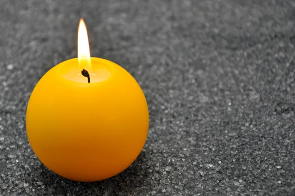 Hořící svíčka v šedý písek — Stock fotografie