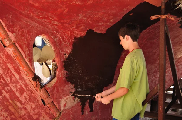 Мальчик-подросток рисует корпус парусника на ролике — стоковое фото