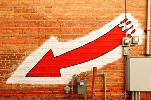 Seta vermelha pintada em uma parede de tijolo — Fotografia de Stock