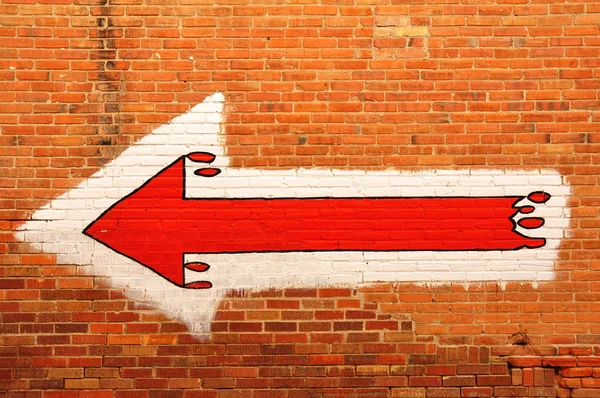 Червона стрілка, намальовані на цегляна стіна — стокове фото