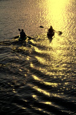 Man and Woman Kayaking at Sunset clipart