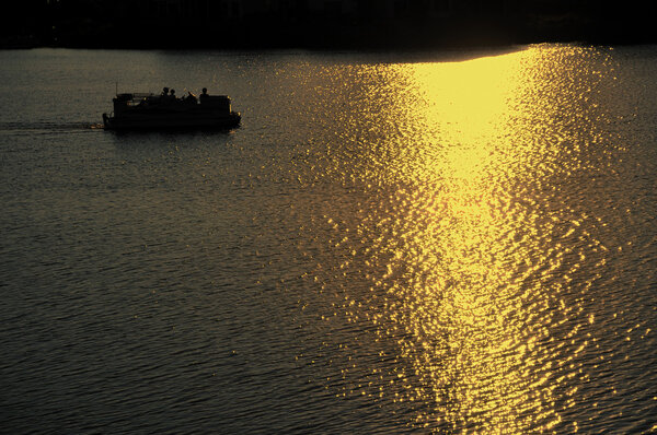 Pontoon Boat Motoring on Lake at Sunset