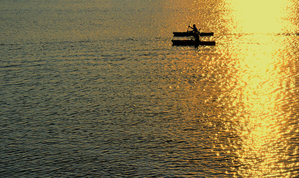 Silhouette of Man and Woman Kayaking on Ocean at Sunset